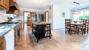 A spacious kitchen with wooden cabinets, a central island, and a dining area with wooden chairs and a table.