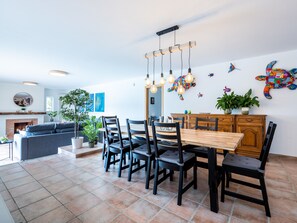 A dining area with a wooden table and chairs, a fireplace, and a large plant.
