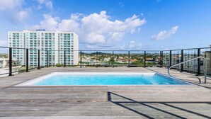 Una piscina sul tetto con vista libera su un hotel e gli edifici circostanti.