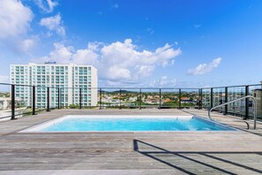 A rooftop pool with a clear view of a hotel and surrounding buildings. - Prime Aruba Location: 2BR Condo near Palm Beach (Noord)
