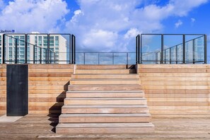 A wooden staircase leading to a glass railing overlooking a cityscape. - Stylish 2BR Condo w/ Pool near Palm Beach (Noord)