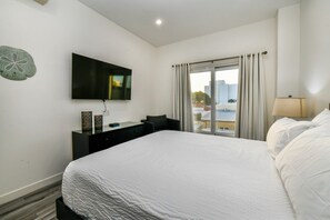 A hotel room with a bed, a desk, a flat-screen TV, and a window with curtains. - Stylish 2BR Condo w/ Pool near Palm Beach (Noord)