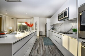 A modern kitchen with white cabinetry, a marble backsplash, and stainless steel appliances. - Stylish 2BR Condo w/ Pool near Palm Beach (Noord)