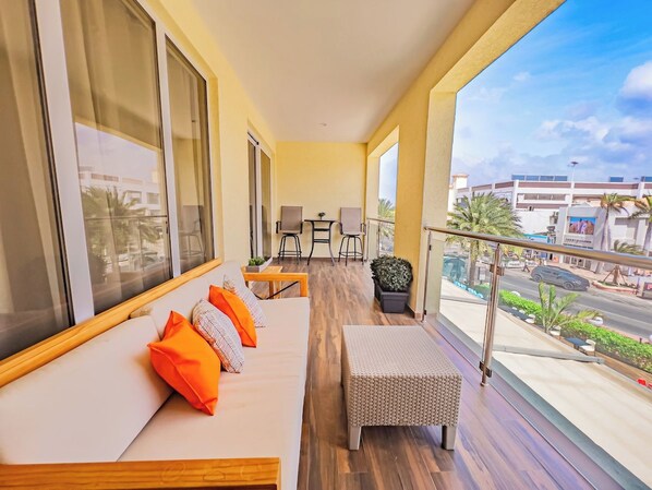 A balcony with a sofa, chairs, and a small table.