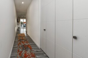 A hallway with a patterned carpet, white tiled walls, and a door on the right. - Stylish 2BR Condo w/ Pool near Palm Beach (Noord)