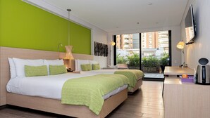 A modern hotel room with a large bed, a desk, and a view of the city.