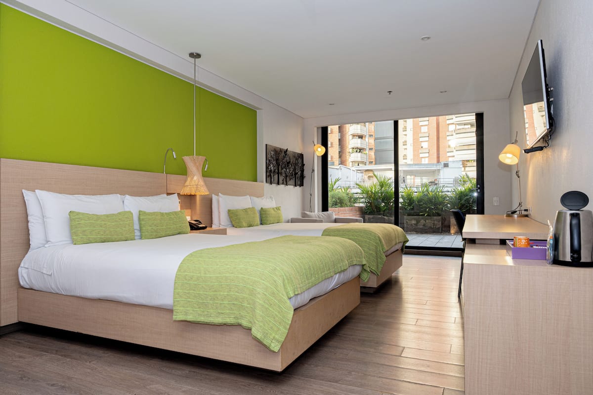 A modern hotel room with a large bed, a desk, and a view of the city.