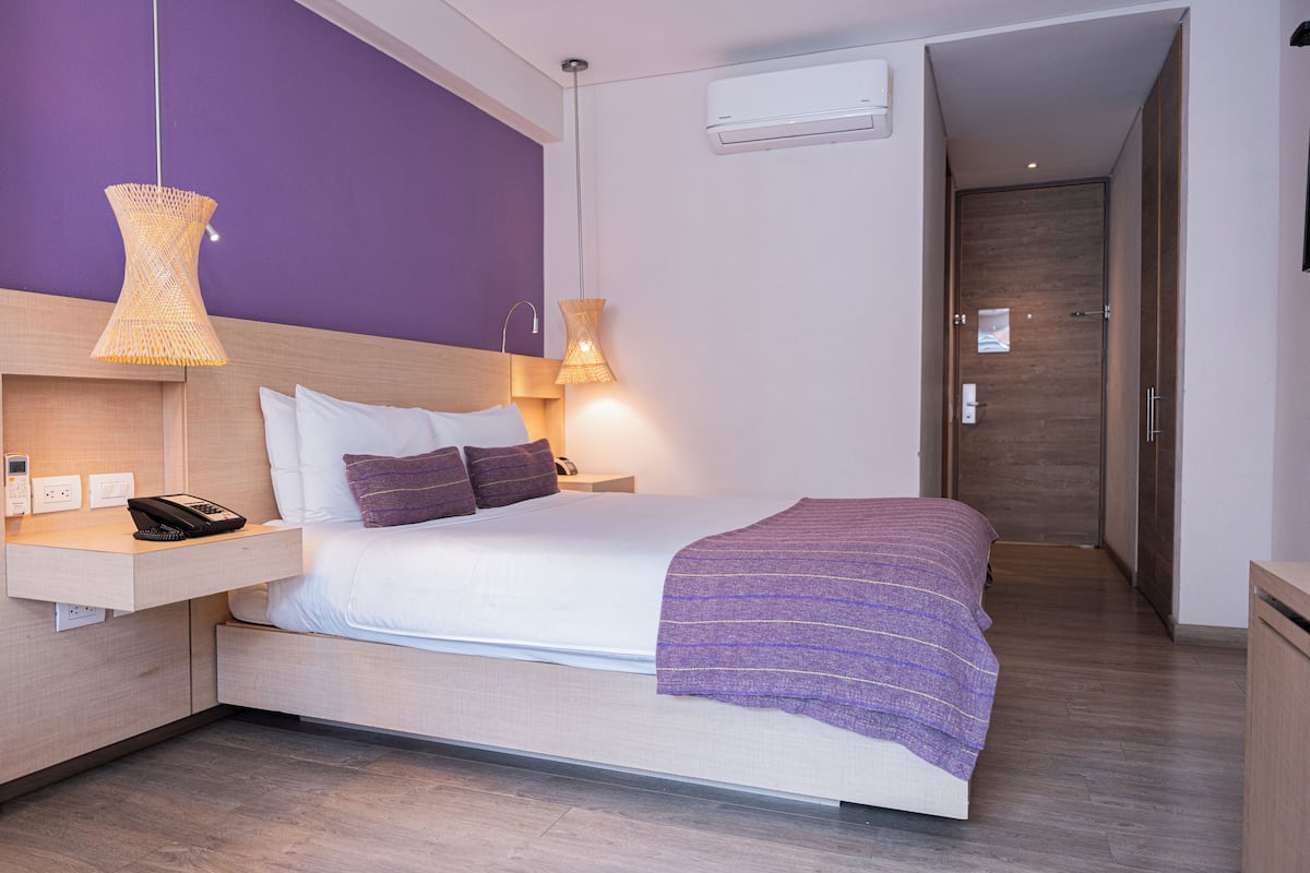A modern hotel room with a bed, bedside table, and a nightstand.