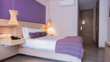 Habitació d'hotel moderna amb un llit, una taula de nit i una petita taula auxiliar.