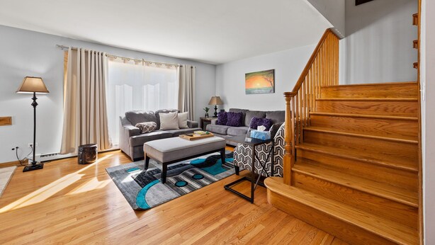 A modern living room with a wooden staircase, a sofa set, a coffee table, and a lamp. - Cheerful 3 bedroom. Feels like home. (Chicago)