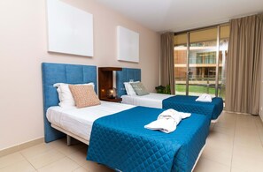 Une chambre d’hôtel avec deux lits, une grande fenêtre et une vue sur un bâtiment à l’extérieur.