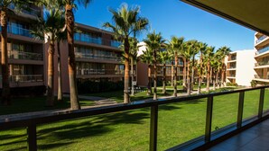 Ein Hotel mit mehreren Etagen, Palmen und einem gepflegten Rasen.