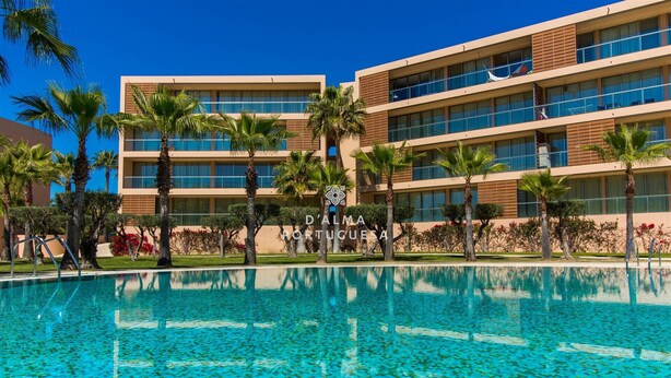 Ein Hotel mit Schwimmbad, Palmen und blauem Himmel.