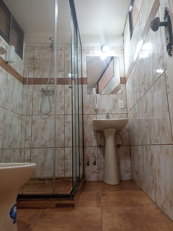 A bathroom with a glass-enclosed shower, a pedestal sink, and a toilet. - RIXAA Hotel (La Paz)