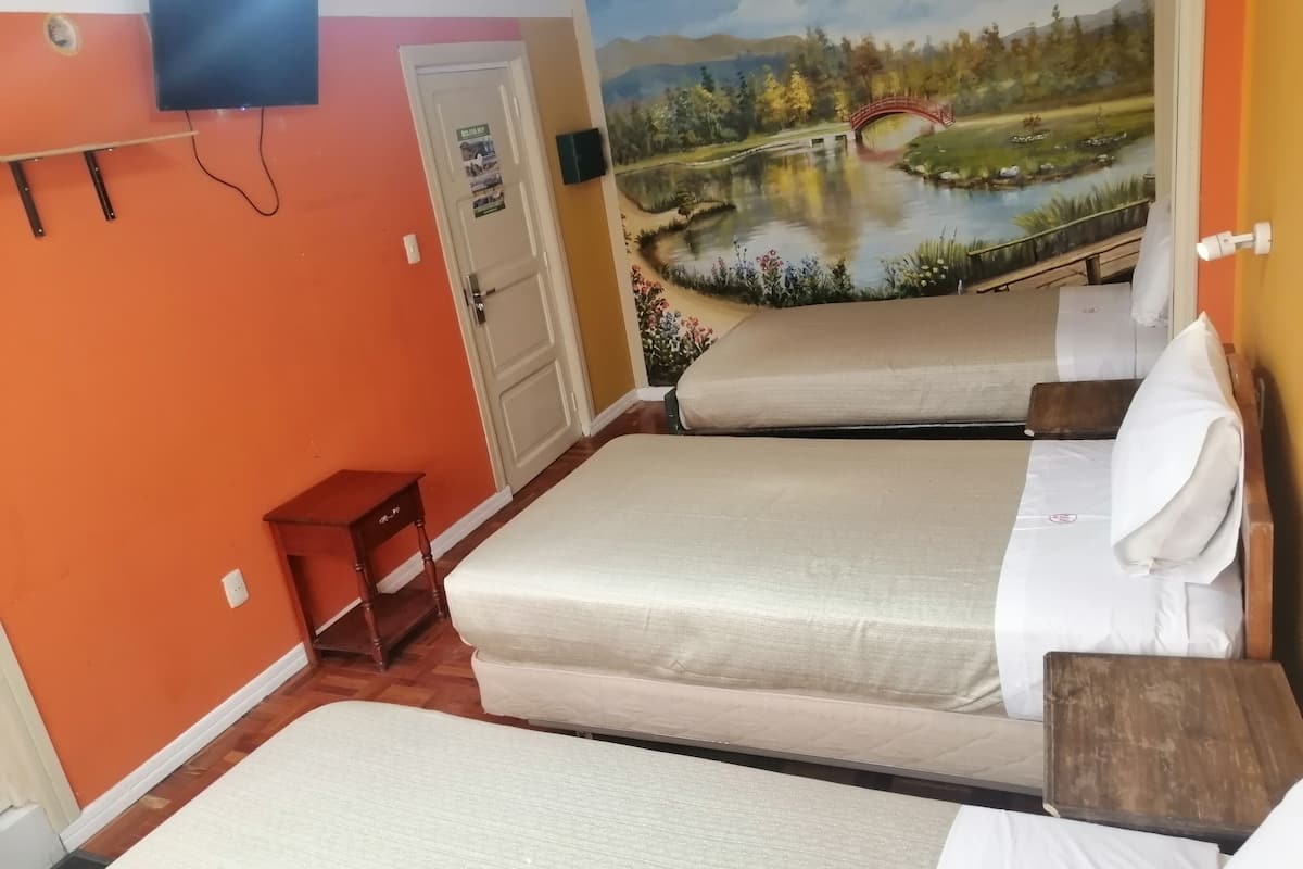 A room with two beds, a TV mounted on the wall, and a door with a poster.