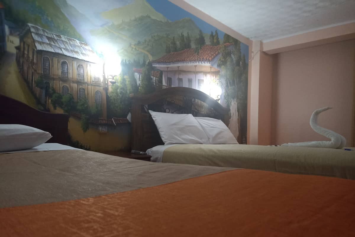 A hotel room with two beds, a mural of buildings on the wall, and a wooden headboard.