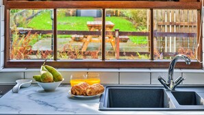 Una cucina con un piano di lavoro in marmo, un lavello e una finestra vista giardino.