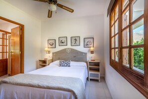 A bedroom with a bed, bedside tables, wall-mounted lamps, and framed artwork.