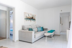 A modern living room with a grey sofa, a small white table, and a teal throw blanket.
