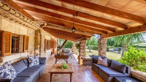 An outdoor patio with a wooden ceiling, stone walls, and a mix of seating arrangements including sofas and a table. - Villa Costa by JS Villas (Port de Pollença)