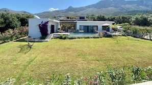 Een modern huis met een zwembad, omringd door een verzorgd gazon en bloeiende planten.