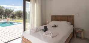 Een slaapkamer met een groot bed, een nachtkastje en uitzicht op een zwembad.