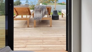 Een kamer met een houten terras, een bed en uitzicht op een meer en bergen.