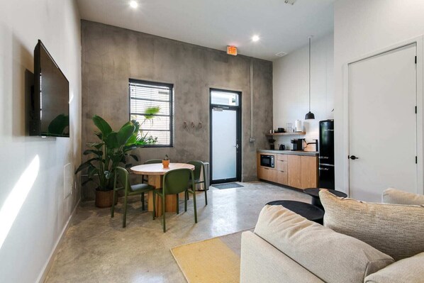 A compact living space with a kitchenette, a dining area with a round table and chairs, a sofa, and a large potted plant. - Claudia - Unit 2 | Sense of Calm and Relaxation, Walking Distance to the Excitem (New Orleans)