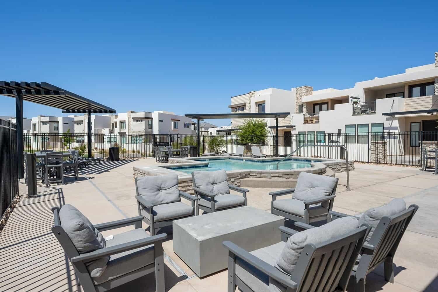 Un área de piscina en la azotea con sillones de descanso y una pérgola.