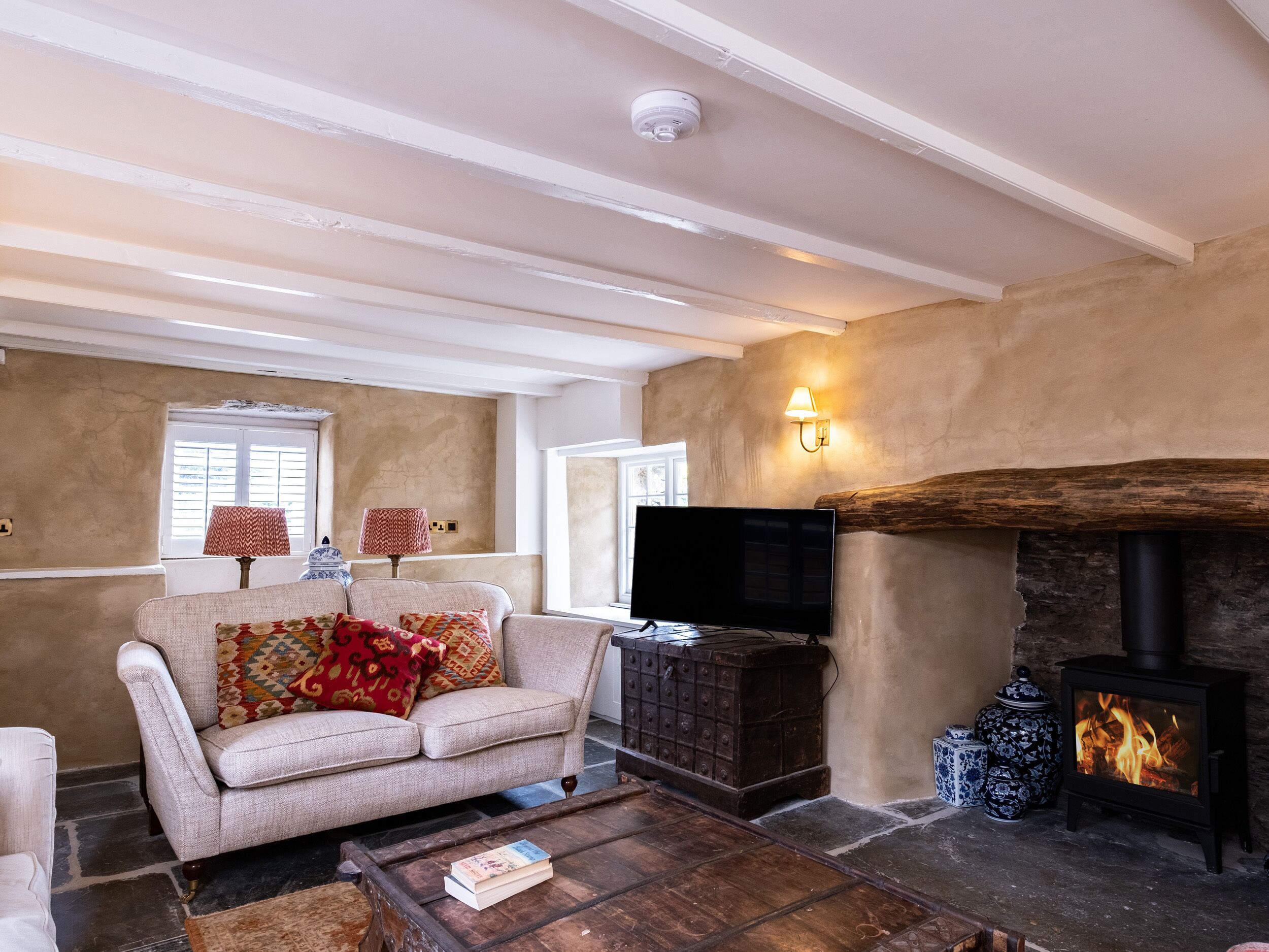 A cozy living room with a fireplace, a sofa, a coffee table, and a television.