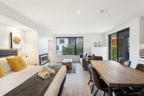 Une chambre d’hôtel moderne équipée d’un lit, d’un canapé, d’une table à manger et d’une grande fenêtre.