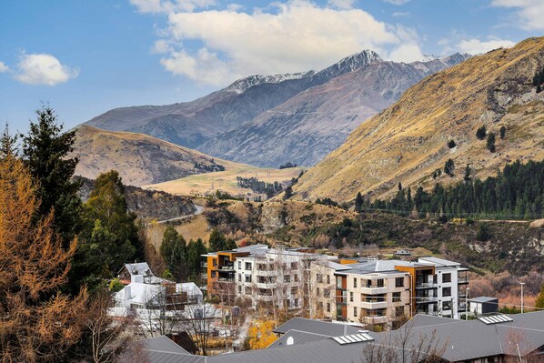 A modern building with multiple floors, surrounded by a mountainous landscape.