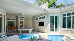 Ein Poolbereich mit Esstisch, Pool und Deckenventilator.