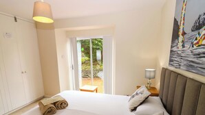 A bedroom with a bed, a nightstand, a lamp, a wardrobe, and a view of the outdoors. - Tayview (Killin)