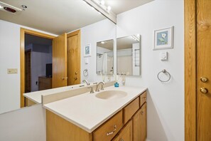 Une salle de bain avec un double vasque, des meubles en bois, un grand miroir et un porte-serviettes.