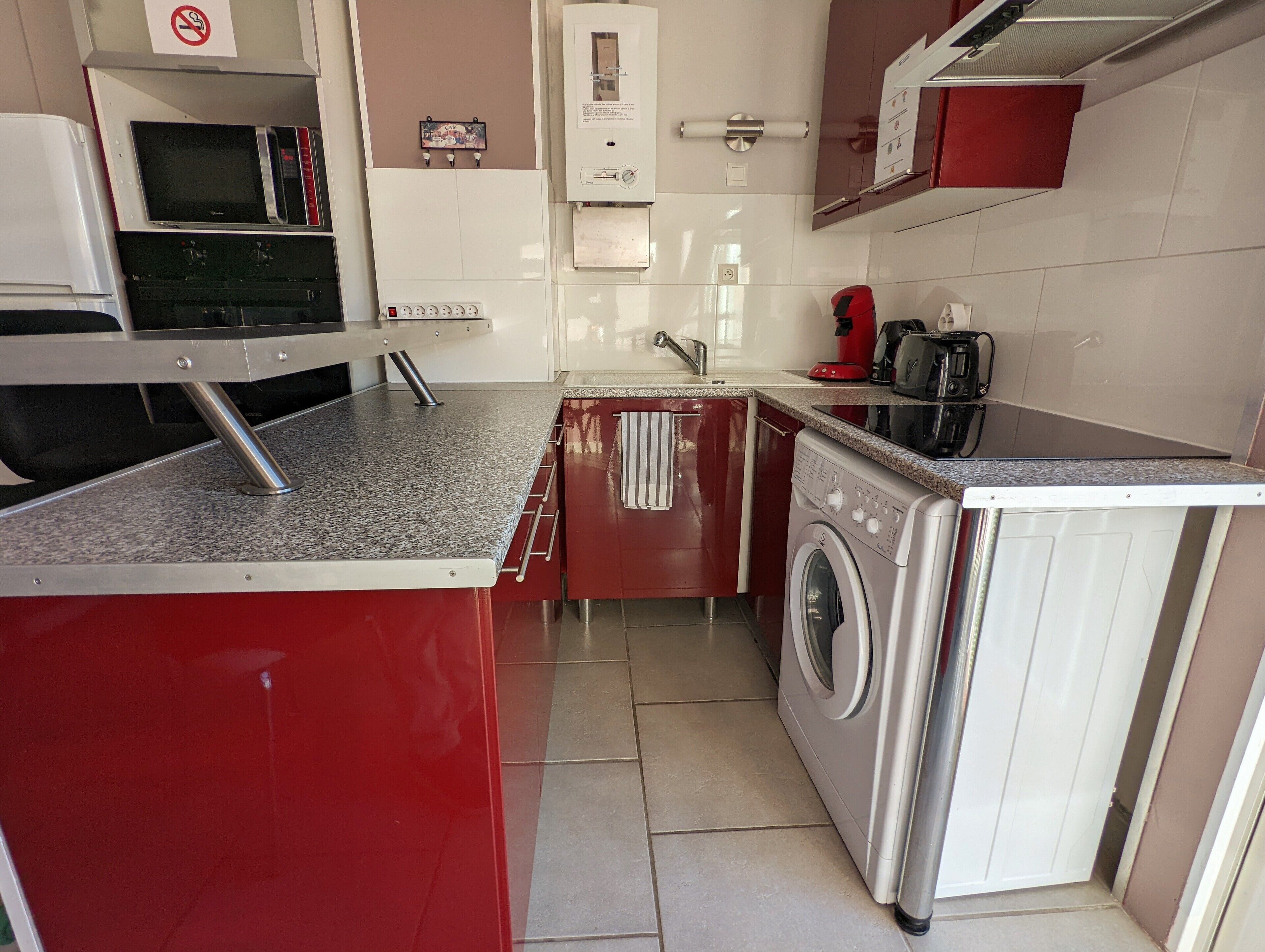 A compact kitchen with a washing machine, a sink, and a microwave.