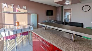 Un espacio habitable compacto con kitchenette, comedor y zona de estar.