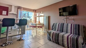 Una sala de estar moderna con un sofá, un televisor montado en la pared y un comedor con sillas y una mesa.