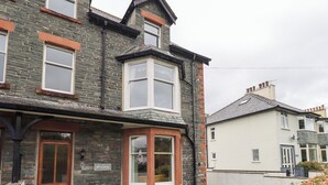 A two-story house with a stone facade, a wooden front door, and a small front garden. - Hazelmere (Keswick)