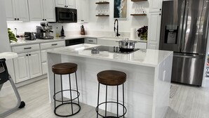 A modern kitchen with white cabinetry, a stainless steel refrigerator, a microwave, and a coffee maker. - Walk to the Beach and everything else (Hollywood)