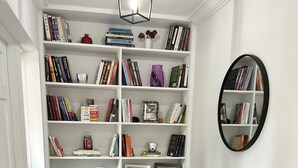 A living room with a bookshelf, a mirror, a blue bench, and a patterned rug. - Walk to the Beach and everything else (Hollywood)