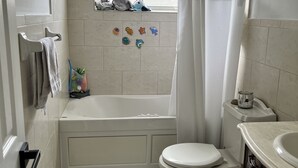A bathroom with a bathtub, toilet, and a window with a view. - Walk to the Beach and everything else (Hollywood)