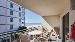 Balcón con mobiliario exterior con vista a una playa y un edificio de hotel.