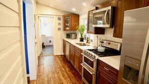 A kitchen with wooden cabinets, a stainless steel refrigerator, a microwave, a stove, and a sink.