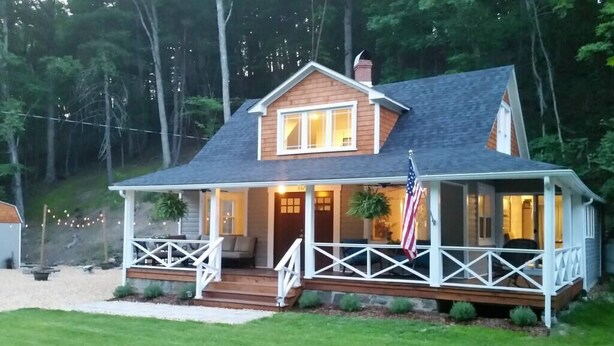 A two-story house with a porch, a small deck, and an American flag.