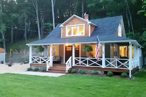 Een huis met twee verdiepingen, een veranda, een klein terras en een Amerikaanse vlag.