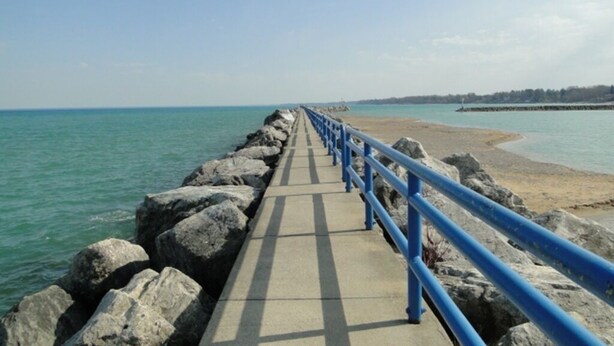 Un camino de concreto con barandas azules que conduce a una playa.