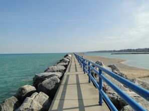 A concrete pathway with blue railings leading to a beach. - Cozy Lexington Cottage! Stroll down to the sandy beach of Lake Huron! (Lexington)
