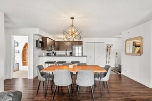 Une cuisine moderne avec des meubles de couleur bois foncé, un îlot central et un luminaire suspendu.