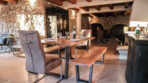 Uma sala de jantar rústica com paredes de pedra, mesas de madeira e cadeiras de couro.